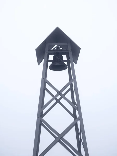 Eine Glocke auf dem Turm im Hintergrund des Himmels. grauer Hintergrund — Stockfoto