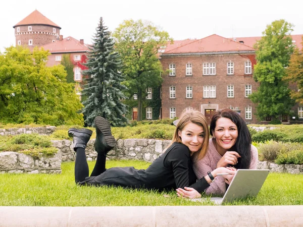Meninas estão deitadas no gramado com um laptop — Fotografia de Stock