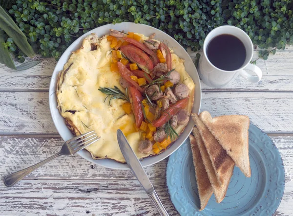 Omelet met groenten en worst op een houten achtergrond. Ontbijt. — Stockfoto