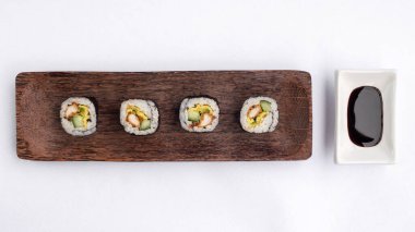 Suşi, tahta bir tabakta yuvarlan. Beyaz bir arkaplanda.