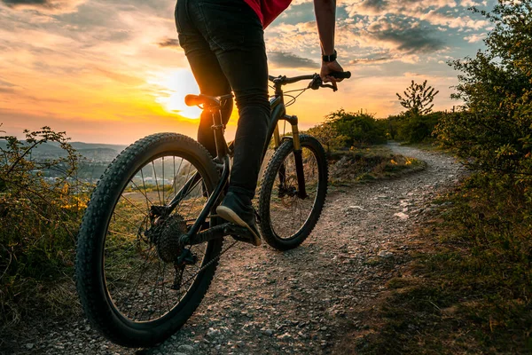 Mountain biker on trail. Back shot of mountain biker at sunset on a modern off-road bike on the hill behind the city. — Stock Photo, Image