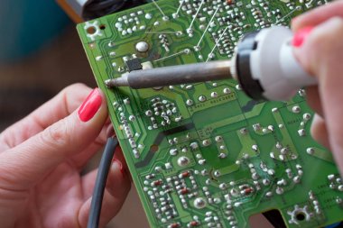Kız-mühendis anahtarlama bir itici güç kaynağı onarır. Montaj ve lehimleme elektronik bileşenleri.
