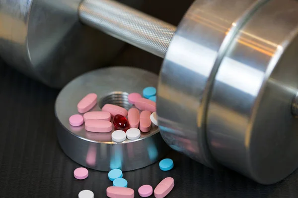 Çelik dumbbell ve spor mat renkli vitamin hapları