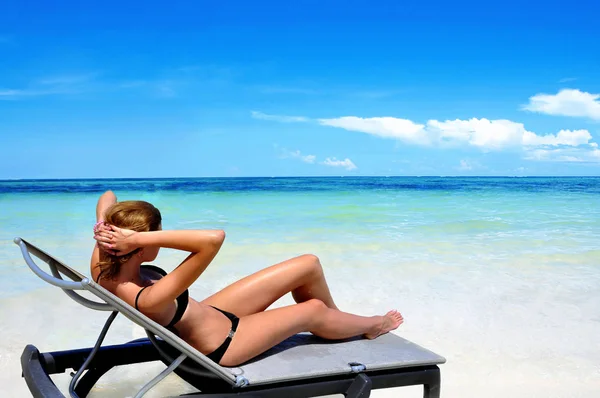 Woman lying on a beach bed near the sea, side view. Stock Photo