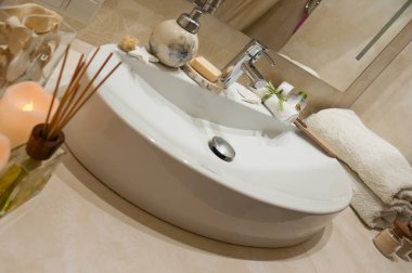 Kaplıca tedavisi havlu, mumlar ve diğer aksesuarları ile bileşimi ile banyo iç. Lüks banyo beyaz porselen lavaboda.