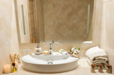 Kaplıca tedavisi havlu, mumlar ve diğer aksesuarları ile bileşimi ile banyo iç. Lüks banyo beyaz porselen lavaboda.