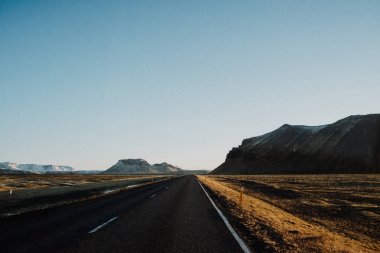 İzlanda'daki bazı dağlar doğru günbatımında önde gelen bir yol