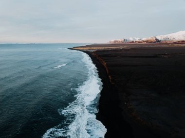 İzlanda'nın sahil siyah kum plaj ve bazı dağ arka planda bir dron fotoğrafı