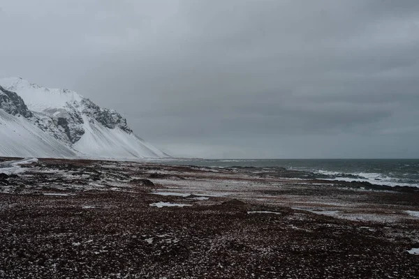 冰岛的粗糙海岸与一些山在背景 — 图库照片