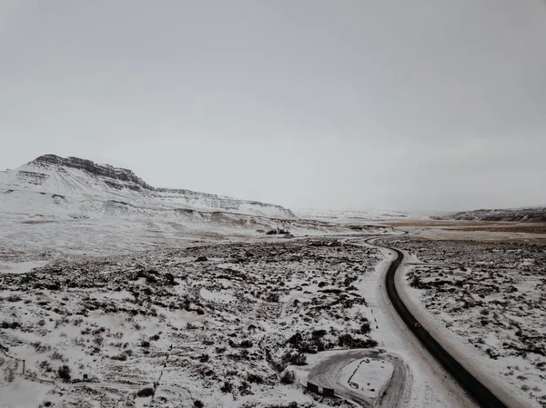 一条有风的公路穿过冰雪覆盖的风景在冰岛 从无人机射击 — 图库照片