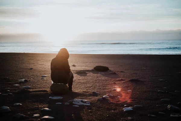 日落时分 一个坐在冰岛黑色沙滩上的人 — 图库照片
