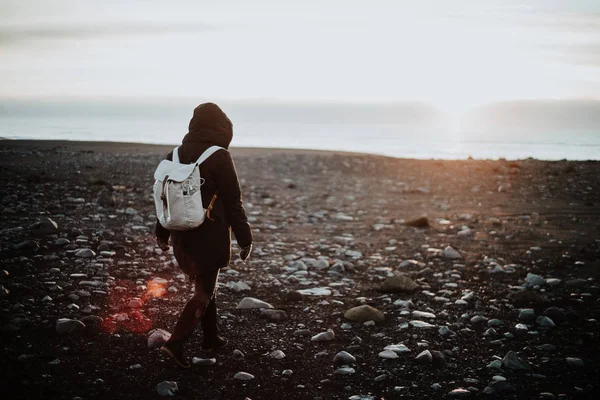 一个人在日落时在冰岛的黑色沙滩上漫步 — 图库照片