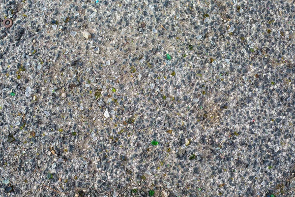 옛 아스팔트의 배경. 작은 바위와 깨진 녹색 유리 조각 이 있는 회색 도로 표면. — 스톡 사진