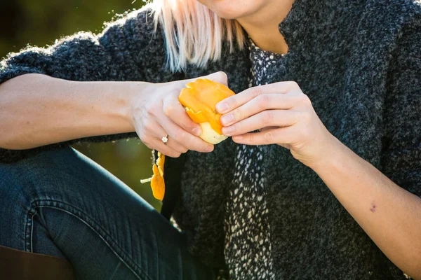 Turuncu yiyen biri. Kadın dışarıda taze portakal kabuğu soyuyor.