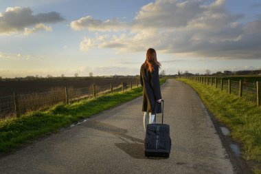 runaway girl standing with her suitcase on the road clipart