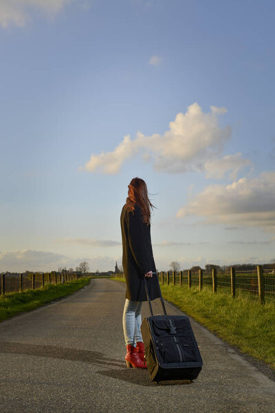 runaway girl standing with her suitcase on the road