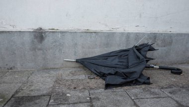broken umbrella is left in the street clipart