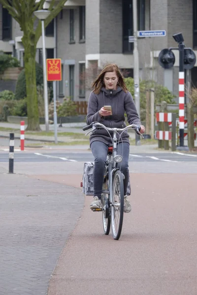 Chica montando una bicicleta y mira a su teléfono inteligente, peligro — Foto de Stock