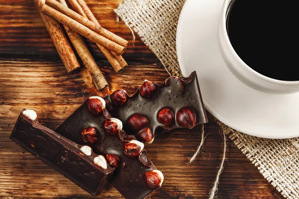 Xícara de café e feijão, paus de canela, nozes e chocolate na woo — Fotografia de Stock