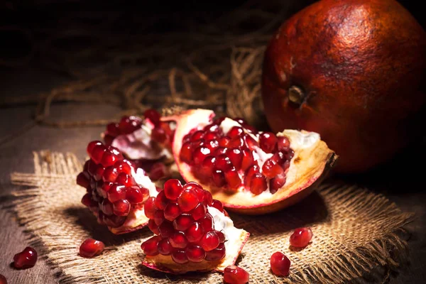 Buah delima segar dengan kacang merah rubi di meja kayu tua — Stok Foto