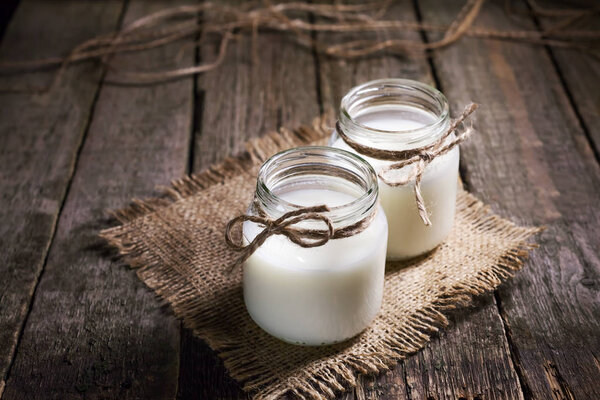 Свежее коровье молоко или сливки в стеклянных бутылках, деревенский стиль, винтаж
 