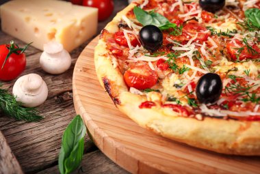 Tahta masada domatesli, peynirli ve mantarlı taze pizza.