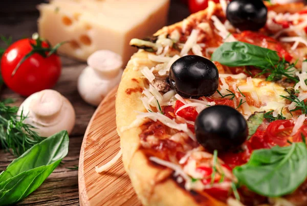 Tahta masada domatesli, peynirli ve mantarlı taze pizza.