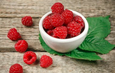 Beyaz rustik ahşap arka plan üzerinde kırmızı taze ahududu. İle kase