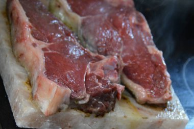 Tuz tabağında iki parça et pişiriliyor.