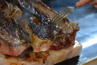 Tuz tabağında et kırıntısı, çatal ve elle.