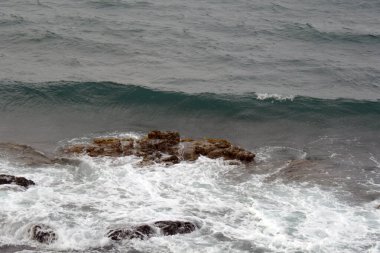 Fırtınalı denizde küçük dalgalar, kıyılarda taşlarla