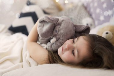Sevimli mutlu küçük kız uyku ve içinde rüya ve onun oyuncak sarılma yatak. Uyuyan çocuğunun fotoğrafı kapatın