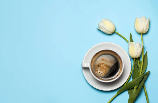 Мінімалістська картина чашки кави та білих тюльпанів на синьому фоні. Концепція весняної кави. вид зверху, плоский ліжко — стокове фото