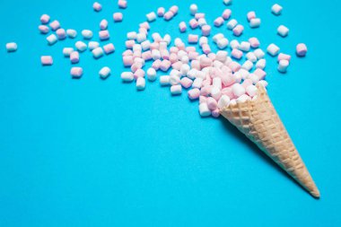 Gözleme koni mavi zemin üzerine pembe ve beyaz marshmallow. Üstten Görünüm, düz yatıyordu. metniniz için boş alan