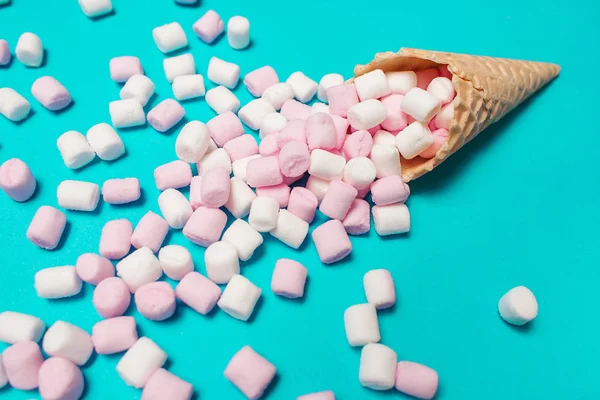 Gözleme koni mavi zemin üzerine pembe ve beyaz marshmallow. Üstten Görünüm, düz yatıyordu. metniniz için boş alan