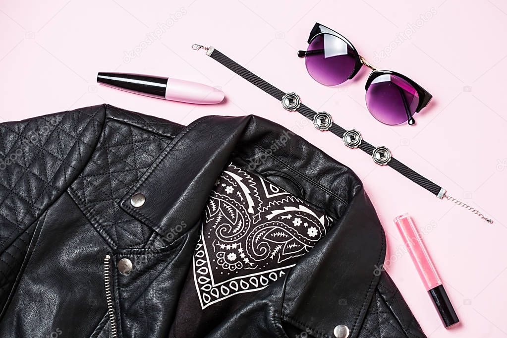 biker jacket and woman sunglasses with decorative cosmetic on pink background. Alternative fashion set. Flat lay, top view