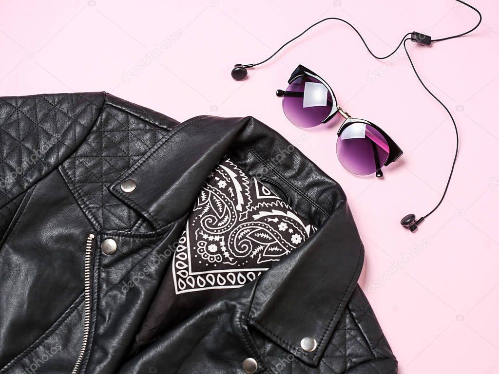 biker jacket and woman sunglasses with headphones on pink background. Alternative fashion set. Flat lay, top view