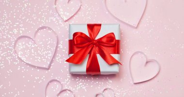 Hediyelik kutu ve kağıt kalpleri pembe bir arka plan üzerinde parlak parıltı vardı. Romantik st. Valentine's gün kavramı selamlar. Üstten Görünüm, düz yatıyordu