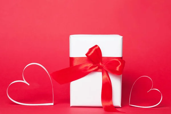 Caja de regalo con corazones sobre fondo rojo. Vista superior, cama plana. San Valentín saludar concepto — Foto de Stock