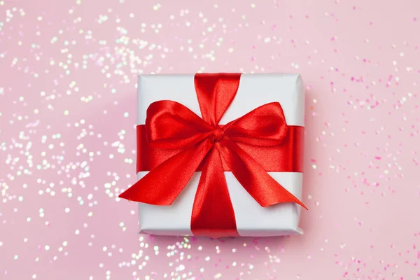 Caja de regalo vith arco rojo y brillo brilla sobre fondo rosa. San Valentín concepto del día — Foto de Stock