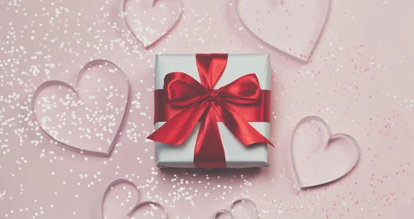 Gift box vith czerwony łuk i brokat błyszczy na różowym tle. koncepcja dzień Świętego Walentego — Zdjęcie stockowe