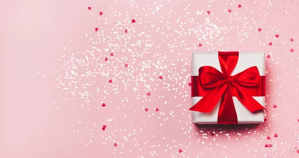 Caja de regalo con brillo brillante sobre fondo rosa. San Valentín romántico concepto de saludos. lugar para su texto. Vista superior, plano — Foto de Stock