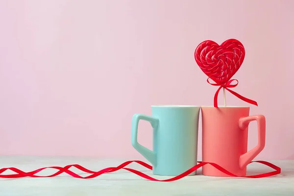 Gros plan de Deux tasses et lolipop en forme de coeur ou bonbons durs sur la table. fond rose. Endroit pour le texte. l'espace de copie. Saint-Valentin concept — Photo