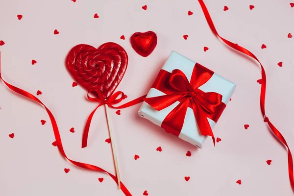 Caja de regalo con lolipop en forma de corazón sobre fondo rosa. San Valentín romántico concepto de saludos. lugar para su texto. Vista superior, plano — Foto de Stock