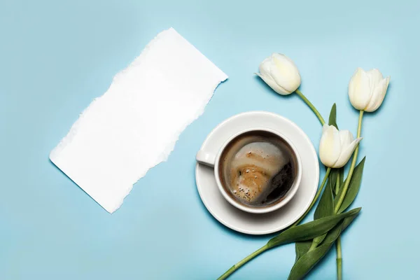 Tazza di caffè e tulipani bianchi su sfondo blu . — Foto Stock