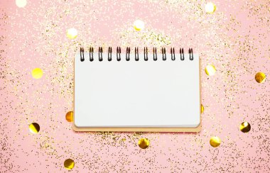 Pembe konfeti arka planında boş not defteri.