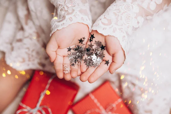 Las estrellas plateadas brillan sobre las manos y las palmas infantiles.. Fotos De Stock Sin Royalties Gratis