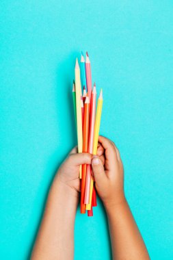 Mavi masa üstü görünümünde boş not defterine el yazısı ile okul malzemeleri ve kırtasiye malzemeleri.