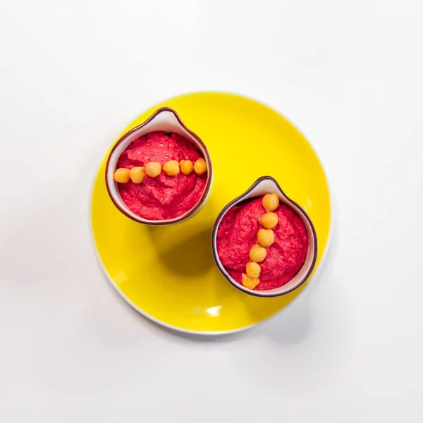 Рожевий хумус з буряком на жовтій яскравій тарілці . — стокове фото