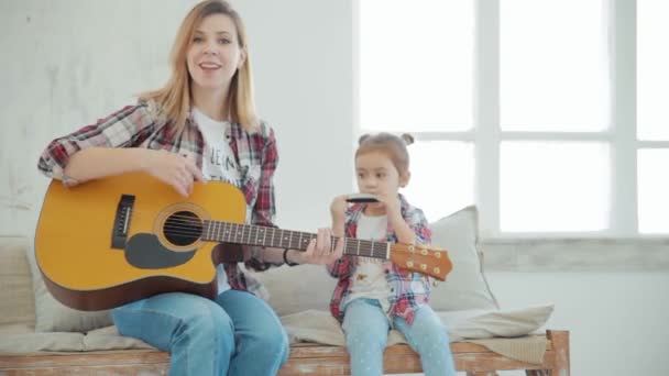 Atraktivní matka a 4-letá dívka hrající na kytaru a harmoniku a zpěv 